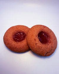 Two strawberry cookies with jelly filling on a white background