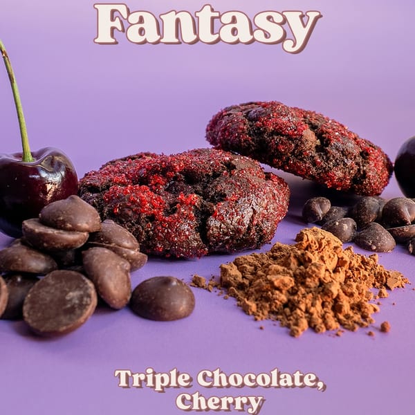 Two triple chocolate cherry cookies with chocolate chips, cocoa powder, and fresh cherries.
